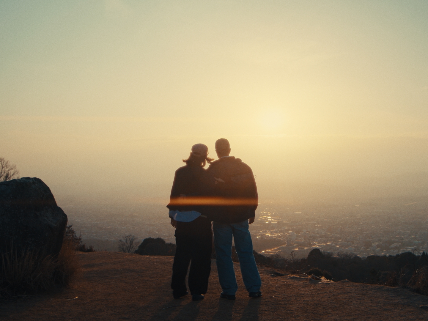 Couple watching sunrise over a misty city from a mountain overlook